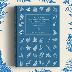 Front cover of the Art Meets Science edition of Anna Atkins' Cyanotypes of British and Foreign Ferns featuring a blue background with white cyanotype prints of various ferns
